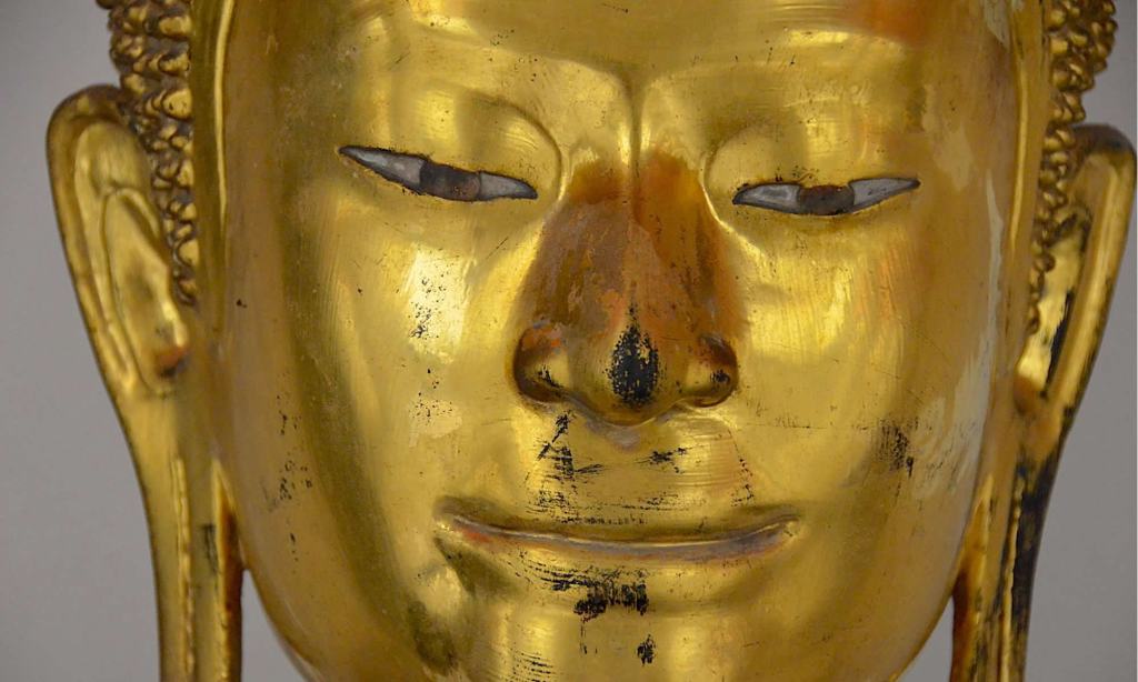 Close up of a golden Buddha statue's eyes, ears, nose and mouth.
