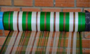 Green and white silk thread is guided onto a roll on a silk farm near Siem Reap, Cambodia.