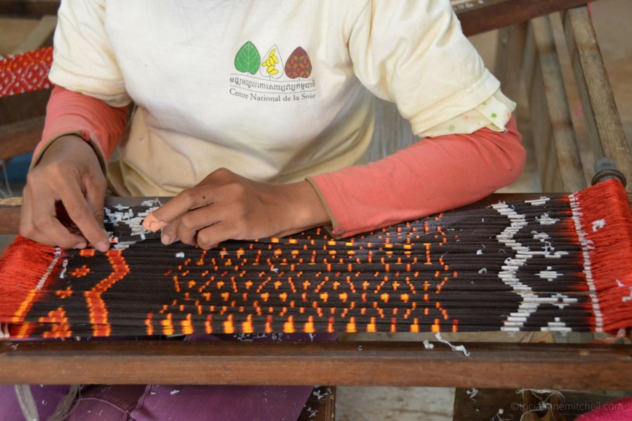 A woman at a Siem Reap, Cambodia silk farm performs the meticulous task of coloring silk thread for Ikat fabric.