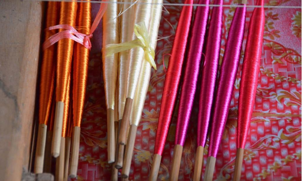 Bobbins of orange, cream, and fuchsia silk inside a drawer at a silk farm near Siem Reap, Cambodia