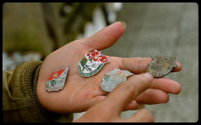 War Items for Sale in Vietnam man holds war medals in hand, in Hue, Vietnam