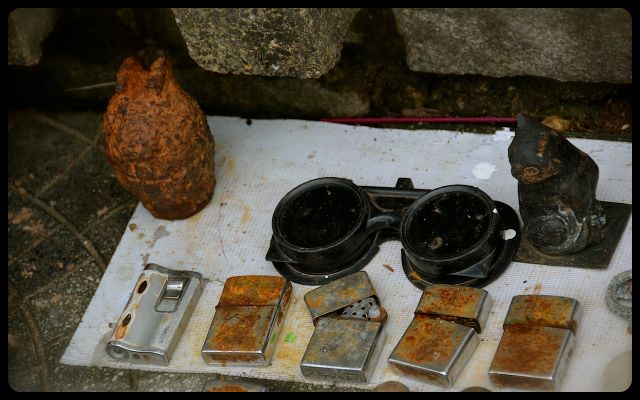 War Items for Sale in Hue, Vietnam rusty grenade and cigarette lighters for sale on Vietnamese sidewalk