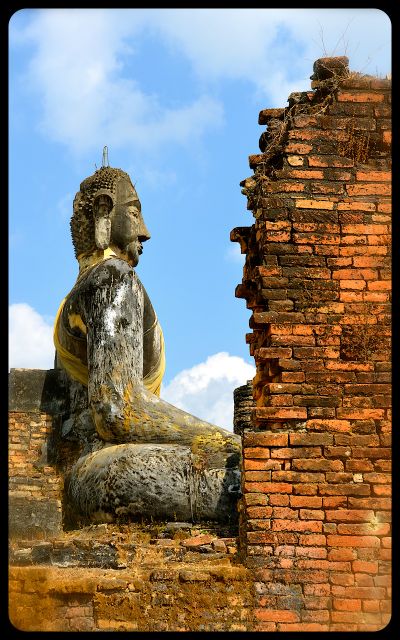 A damaged wall and Buddha statue at Laos' Wat Phia Wat Temple.
