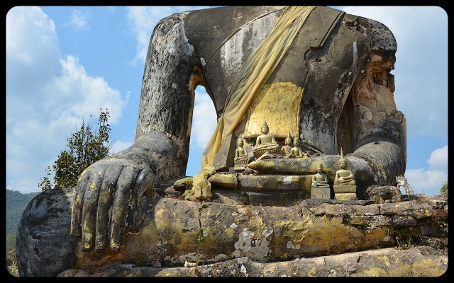 A close-up of the torso of a damaged Buddha statue at the Wat Phia Wat in Laos.
