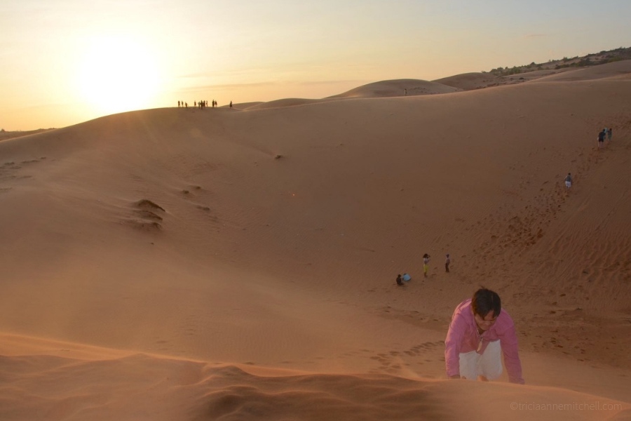 A man climbs Mui Ne's sand dunes on his hands and knees.