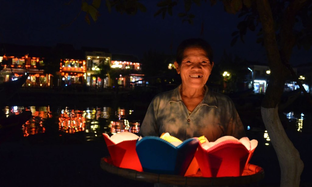 A woman holds a tray of red and blue paper lanterns for sale, in Hoi An, Vietnam.
