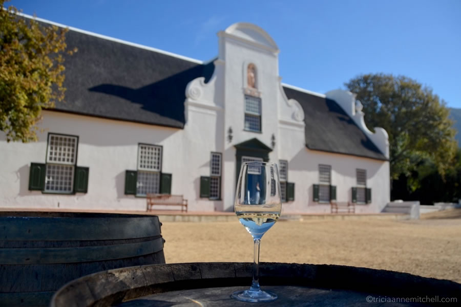 A wine glass sits on a barrel in front of Groot Constantia Winery in South Africa.