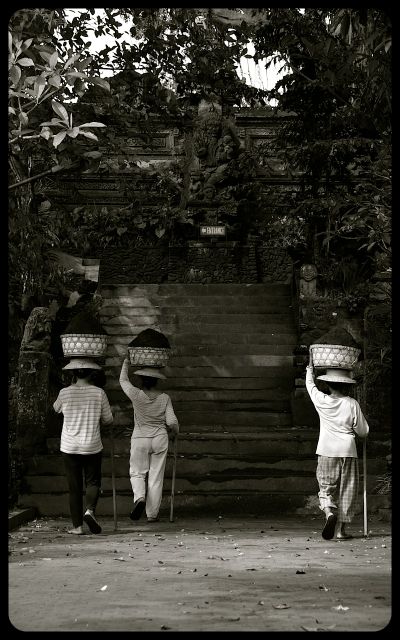 Three ladies carry baskets of soil on their heads in the Indonesian city of Ubud, on the island of Bali.