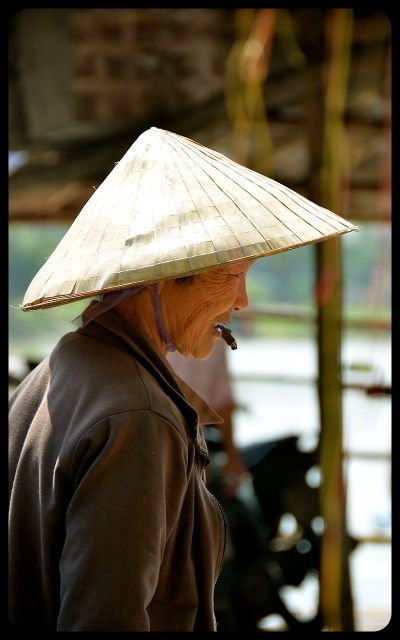Woman smoking with non la hat in Hoi An Vietnam Woman smoking with non la hat in Hoi An Vietnam