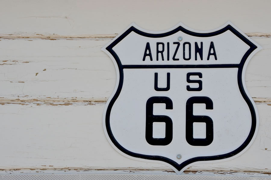 An Arizona Route 66 sign hanging on a white building.