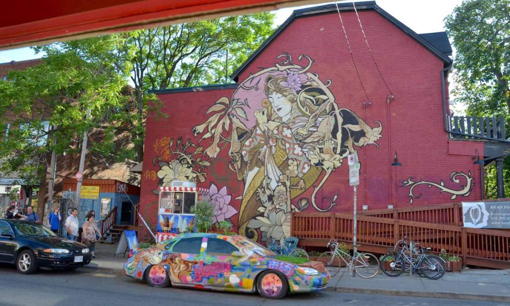 A mural of a woman is painted on a red building in the Kensington district of Toronto.