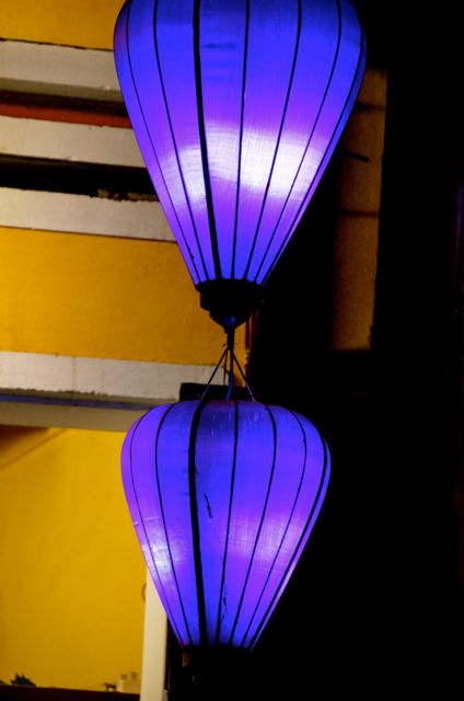 Two purple lanterns are illuminated outside a business in Hoi An, Vietnam. 