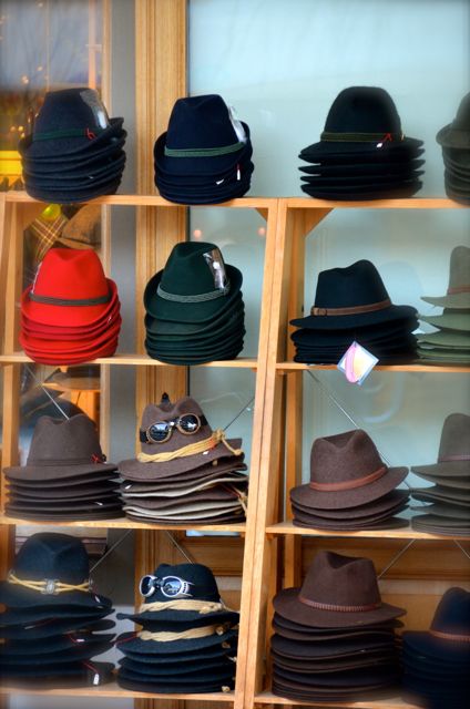 Red, green, blue, grey, and brown winter woolen hats sit on an outdoor  display outside a shop in Oberammergau, Germany.