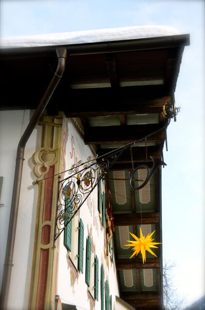 A yellow star decoration hangs on a chalet-style building covered in snow in Oberammergau, Germany.