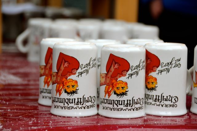 White Christkindlmarkt mugs are stored upside down on a red table at a German Christmas market.