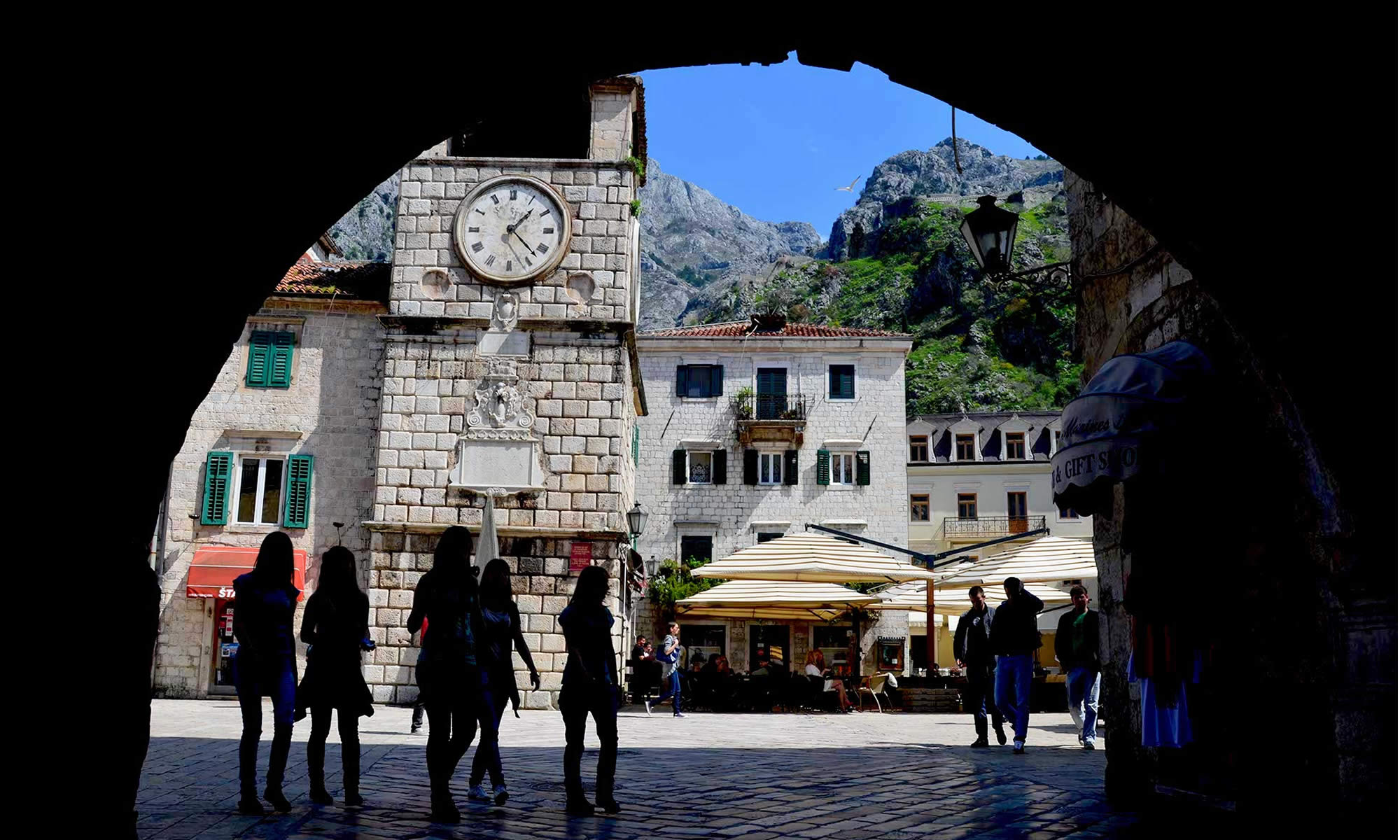 Young women, in silhouetted form, walk through the cobbled streets of the Old Town in Kotor, Montenegro.