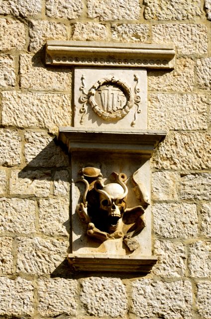 A skull and crest adorn the exterior of a stone building in Kotor, Montenegro.