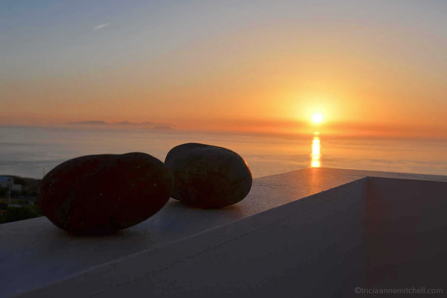 Glimpsed from a balcony, the sun rises over the island of Santorini.