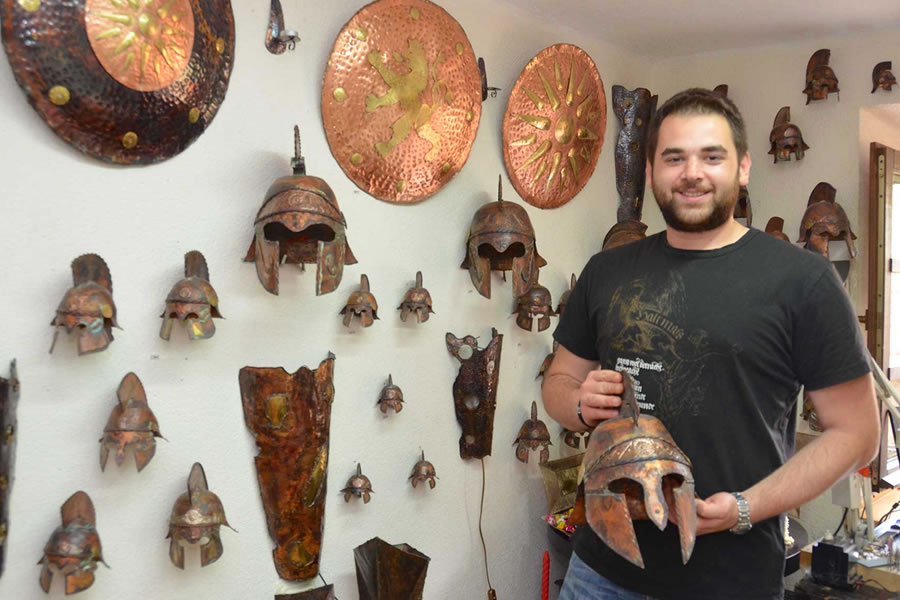 A man, working in a souvenir jewelry shop in Ohrid, Macedonia, holds a reproduction warriors mask, fashioned after those worn in Ancient Macedonia.