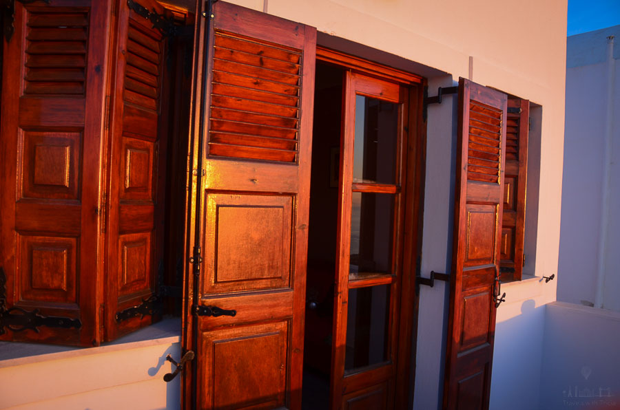 The morning sun illuminates wooden shutters on an apartment in Santorini.