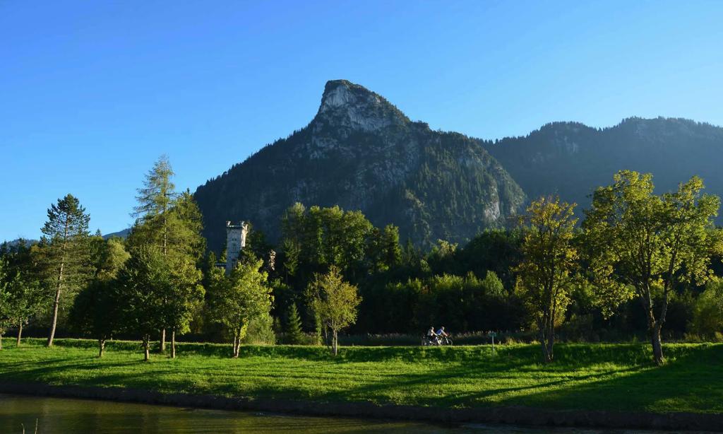A pair of bicyclists ride on a pedestrian lane, in the shadows of Mount Kofel, a mountain peak in Oberammergau, Germany.