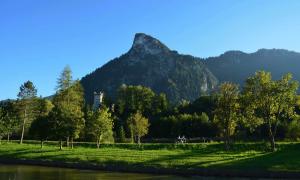 A pair of bicyclists ride on a pedestrian lane, in the shadows of Mount Kofel, a mountain peak in Oberammergau, Germany.