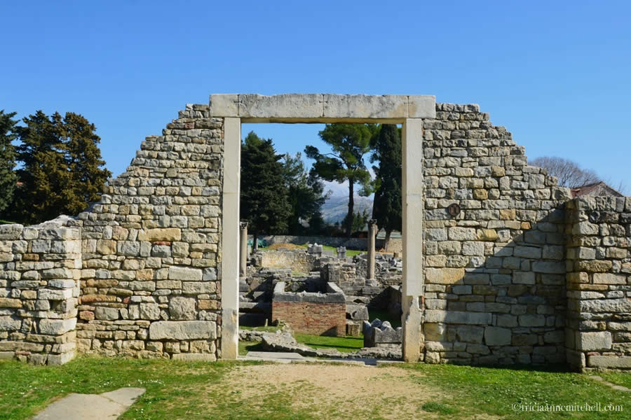 The Manastirine area is visible through the portal of ruined stone facade in the Ancient Roman city of Salona, now Croatia.