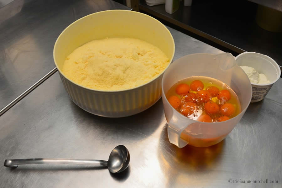 Two bowls sit on a table in the kitchen of a restaurant in Modena, Italy. One is filled with Parmigiano Reggiano cheese; the other is filled with about 20 egg whites and yolks.