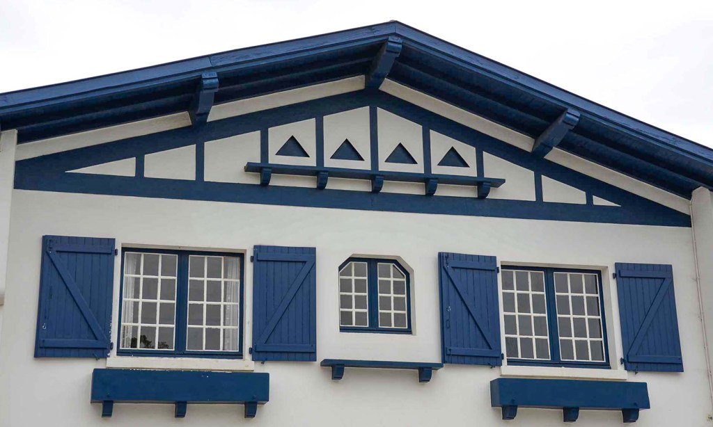 A blue and white house in France's Basque country (Pays Basque) features blue trim, triangles, and shutters.