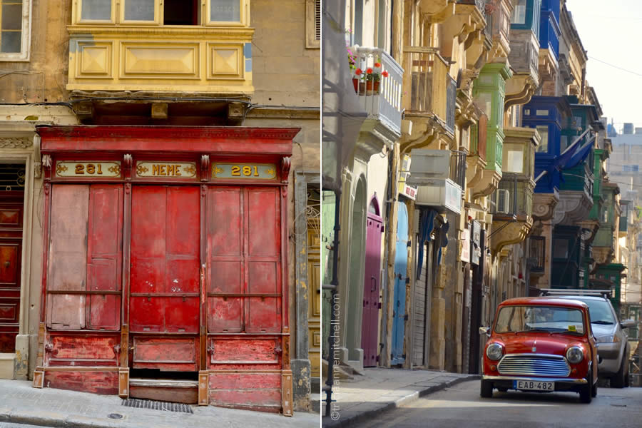 A vintage car drives on a steep Valletta street, past colorful and vintage storefronts.