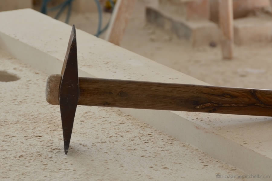 A stonemason's tool lays on a block of white limestone.
