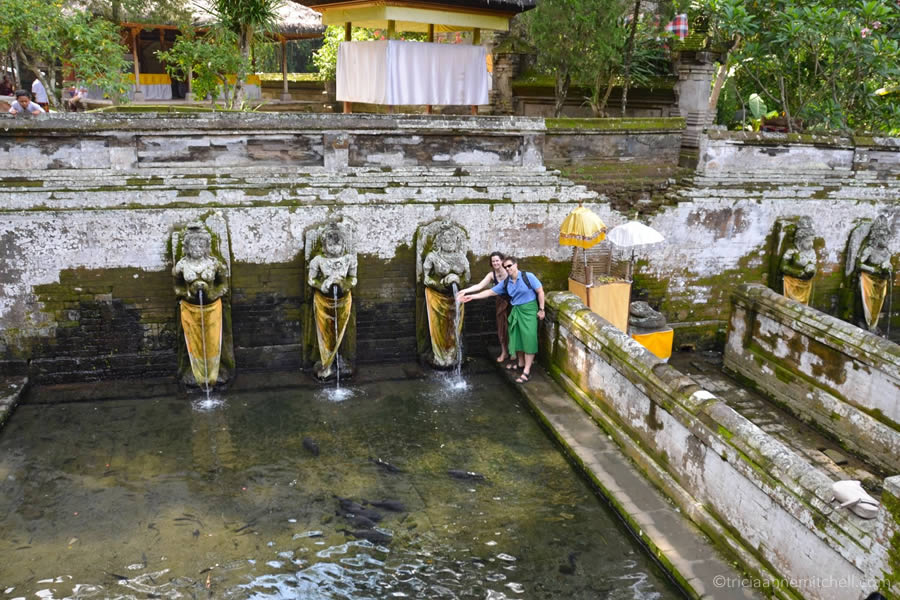 A couple stands next to the holy water spring at Bali's Elephant Cave (Goa Gajah).