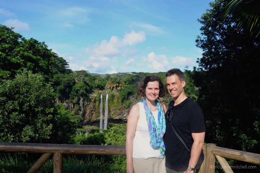 A couple stands overlooking the Chamarel Waterfalls, near the Terres des Sept Couleurs.