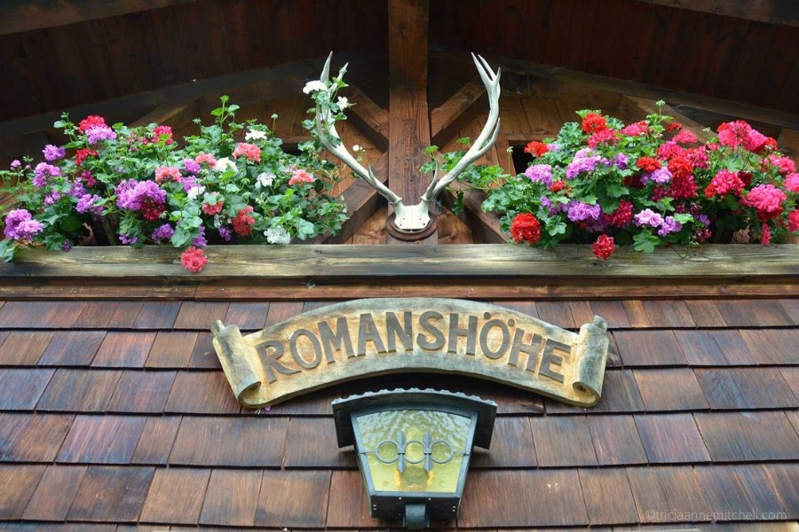 Close-up of a Bavarian restaurant. There are a pair of antlers, red and purple flowers, and a sign that says 