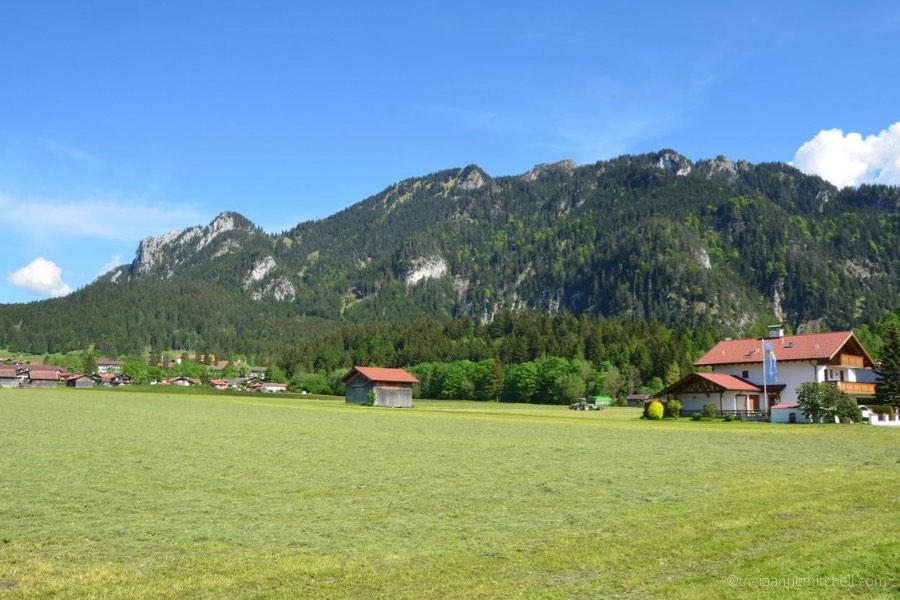 A forested mountain towers over a Bavarian house and wooden barn in the village of Oberammergau, Germany.