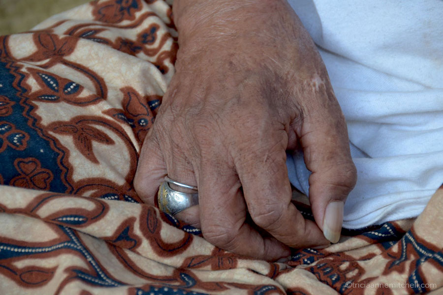 A man's hand rests on his lap.