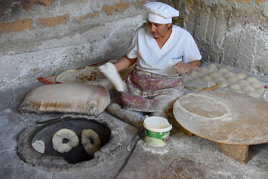 A woman places lavash dough in the oven in the Armenian countryside.