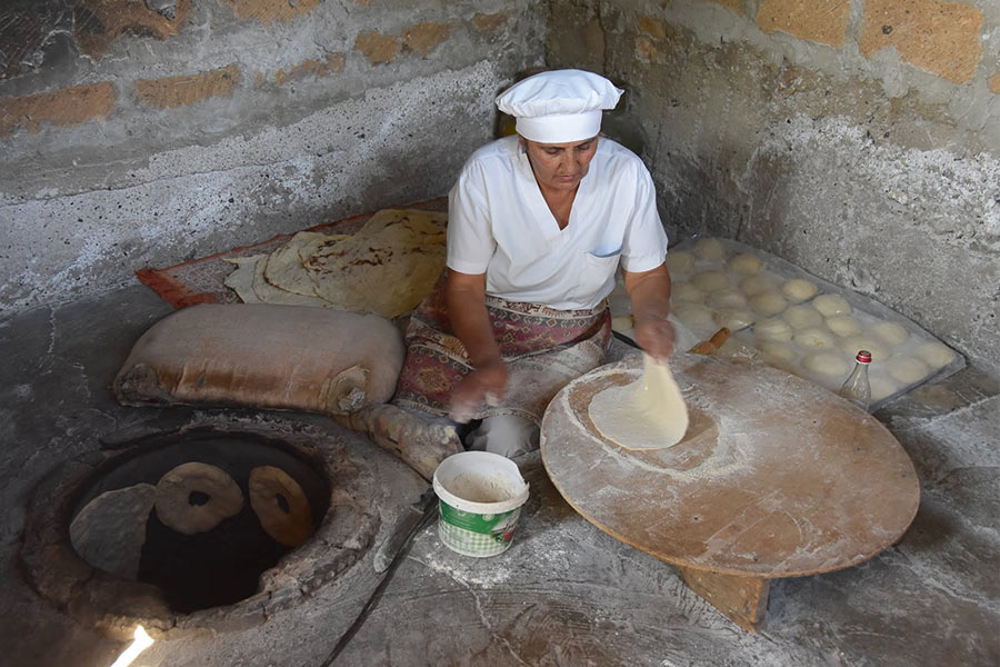 A woman rolls out lavash dough in the Armenian countryside.