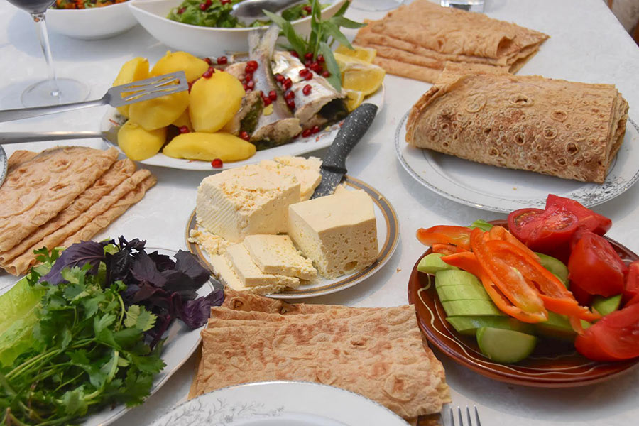 A traditional Armenian meal consisting of fish, white cheese, cucumbers, tomatoes, peppers, lavash, and boiled potatoes.