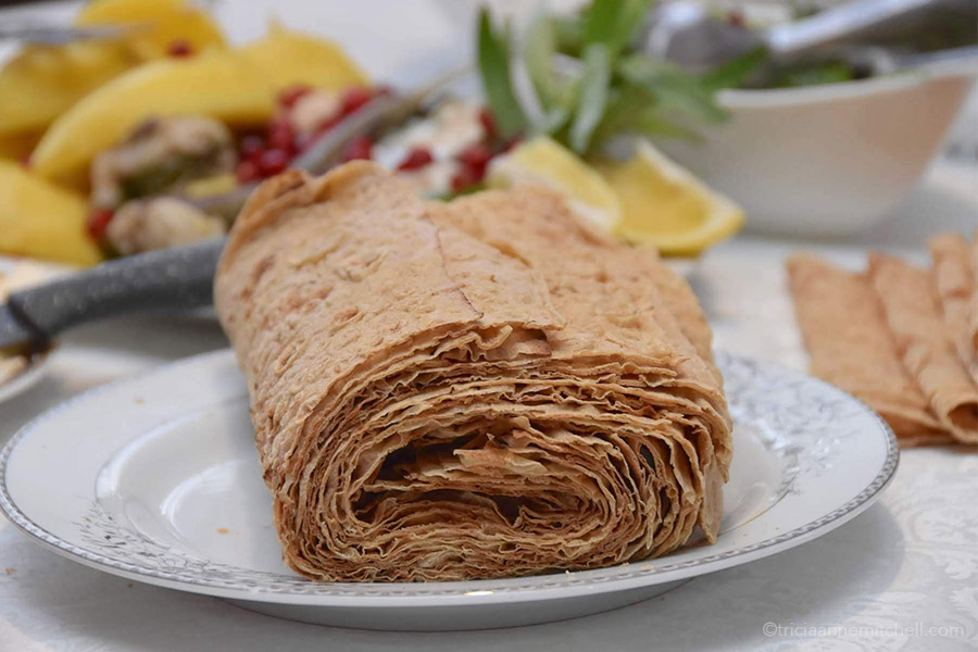 Sheets of lavash, rolled into a tube-like shape on a dining table.
