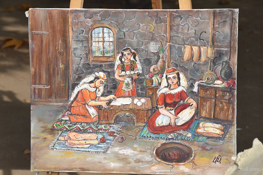 A painting at the Vernissage open-air market depicts women in traditional dress baking lavash.