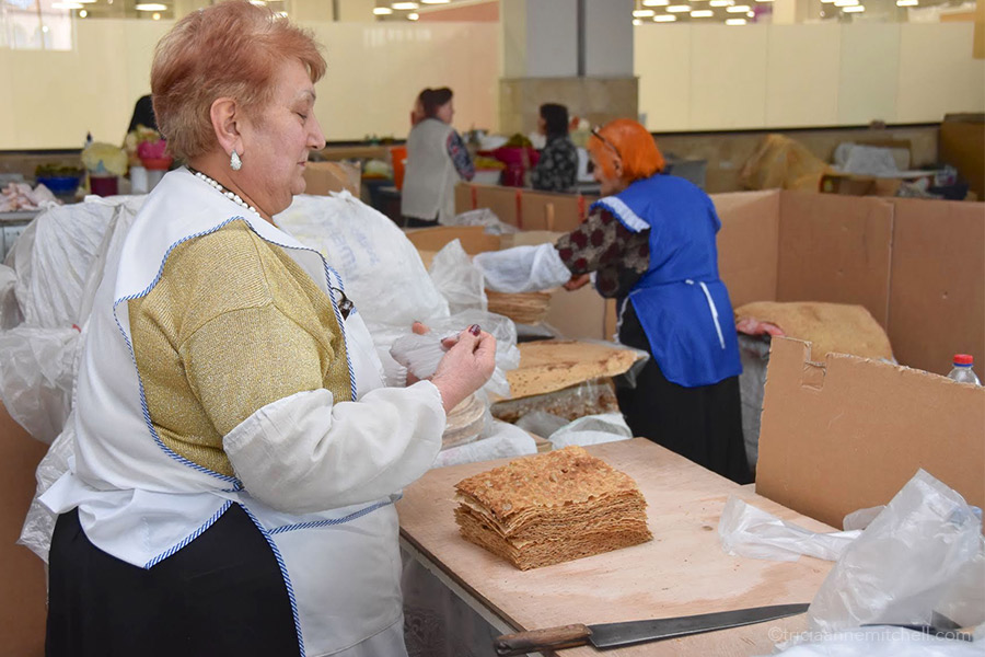 A vendor stacks sheets of lavash at a Yerevan fresh-food market.