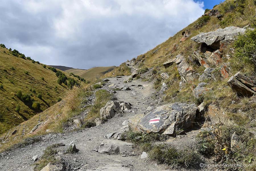 A white and red trail rectangular symbol painted on a rock indicates the correct trail leading to the Gergeti Church near Kazbegi, Georgia.
