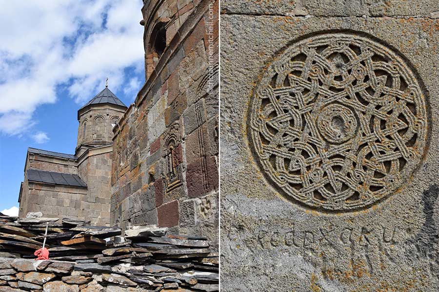 Left: The tower and pinkish-beige wall of the Gergeti Trinity Church near Kazbegi, Georgia. Right: On a wall, an intricate circular symbol is carved. There is centuries-old graffiti below it.