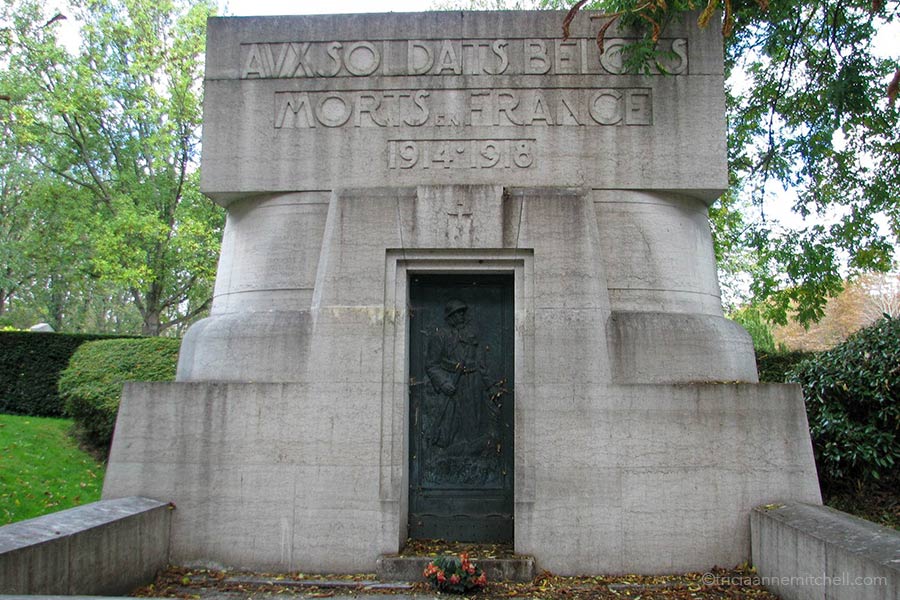 A grey stone monument with a dark green metal door in the Pere Lachaise Cemetery in France. The carved words on the top of it read: "Monument aux soldats belges morts en France."
