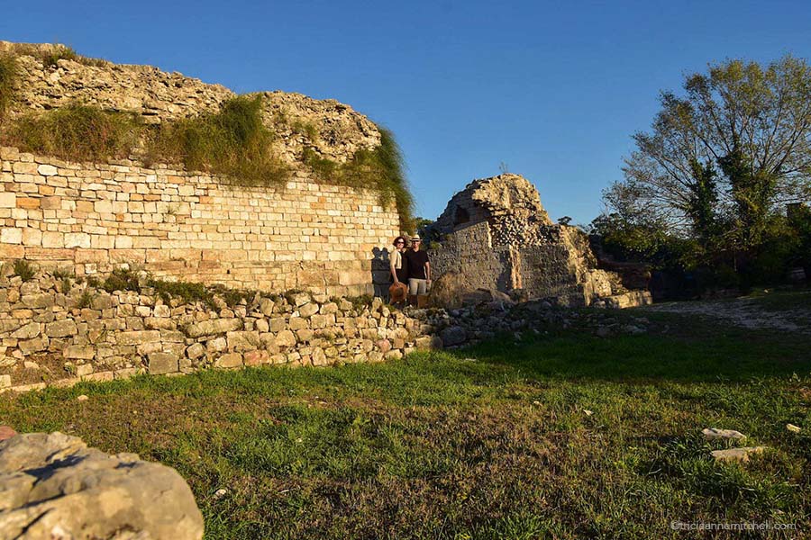 A man and woman stand next to the stone ruins of the Porta Caesarea (Caesar’s Gate) in the ancient Roman city of Salona, now Croatia.