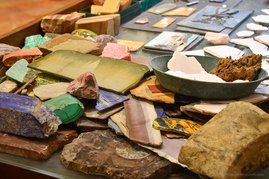 The desk of a Florentine master mosaicist is covered with semi-precious stone samples ranging from blue lapis lazuli to green malachite.