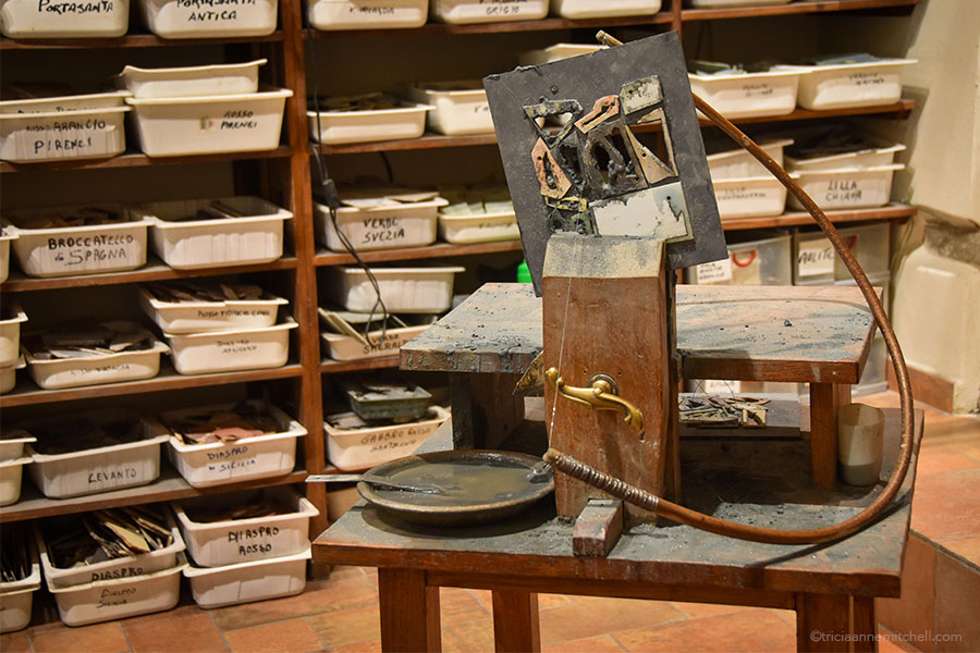 One of the desks used to cut the stone fragments. Resting on the desk are a wooden bow saw and a small bowl filled with grey liquid, including water and silicon carbide.