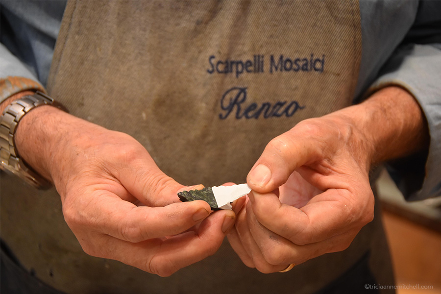 The master artisan removes the white adhesive paper outline and washes the dust away from the newly cut stone fragment.