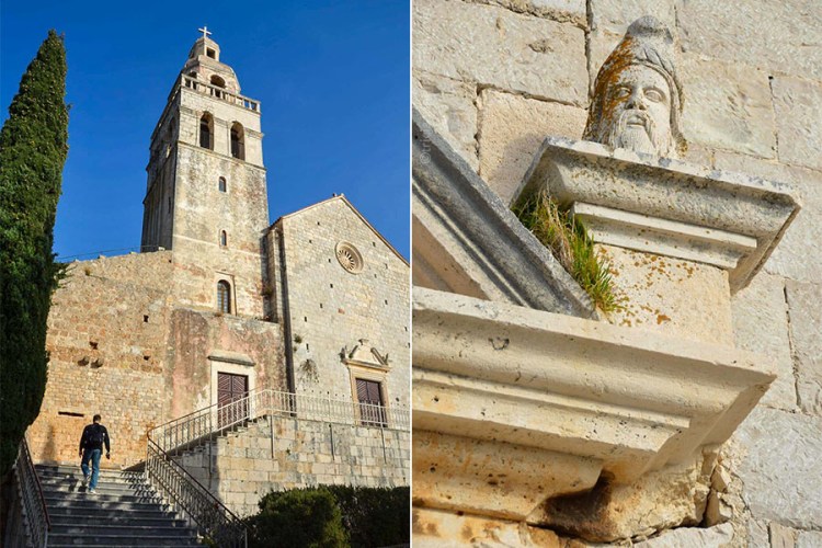 The white stone belltower of a an old church in Komiza, Croatia. A man is walking up stairs to the church's terrace.